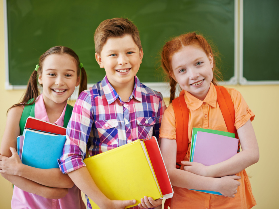 Small group of school friends looking at camera on background of blackboard