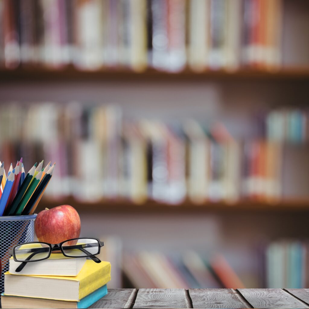 digital composite of School materials and apple with library background